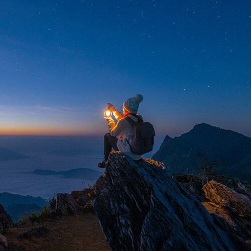 Odgers Berndtson personne avec une lampe assise au sommet d'une montagne au coucher du soleil